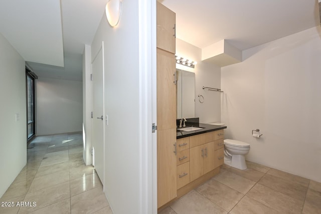 bathroom with toilet, vanity, and tile patterned flooring