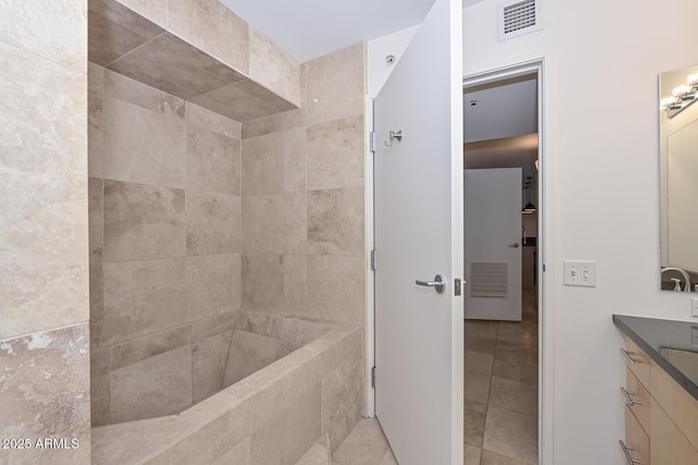 bathroom with a tile shower, tile patterned floors, and vanity