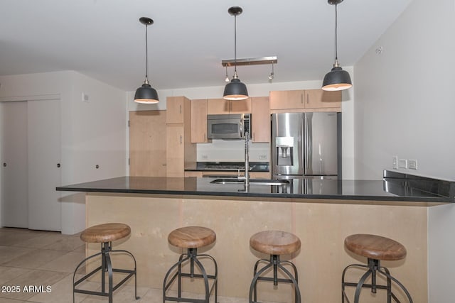 kitchen featuring decorative light fixtures, light tile patterned floors, light brown cabinetry, and stainless steel appliances