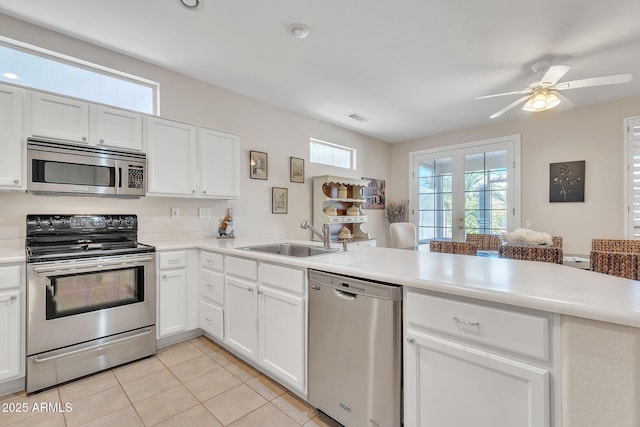 kitchen featuring stainless steel appliances, light countertops, visible vents, a sink, and a peninsula