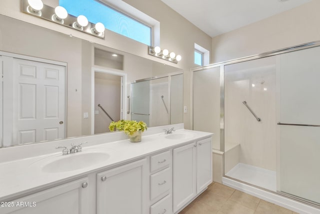 full bathroom with tile patterned flooring, a sink, a shower stall, and double vanity