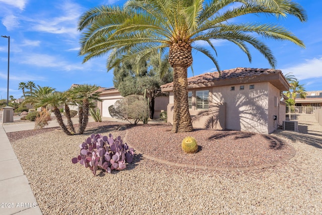 view of front of home featuring driveway, a tile roof, central AC unit, and stucco siding