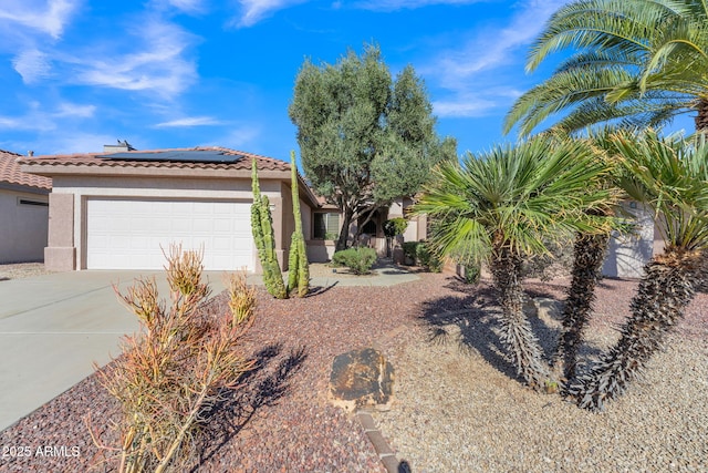 view of front of property with an attached garage, roof mounted solar panels, concrete driveway, and stucco siding