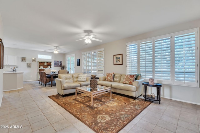 living area with a ceiling fan, baseboards, and light tile patterned floors