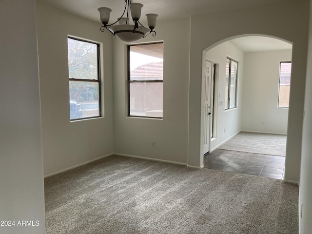 unfurnished room with carpet floors and a chandelier