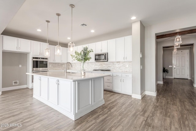 kitchen featuring appliances with stainless steel finishes, white cabinetry, and a kitchen island with sink