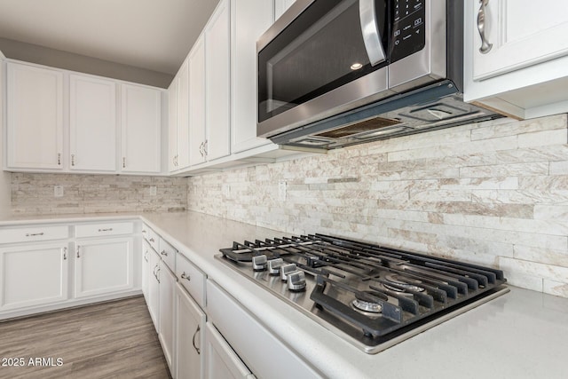 kitchen with white cabinetry, stainless steel appliances, and tasteful backsplash