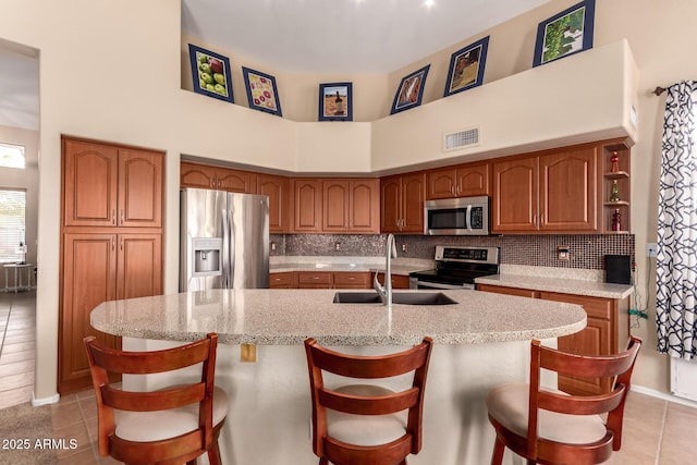 1453 E Elgin Pl, Chandler, AZ 85225 - kitchen with stainless steel appliances, a sink, brown cabinetry, light tile patterned floors, and a towering ceiling