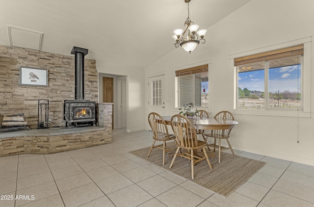 dining area featuring light tile patterned floors, vaulted ceiling, baseboards, a wood stove, and a notable chandelier
