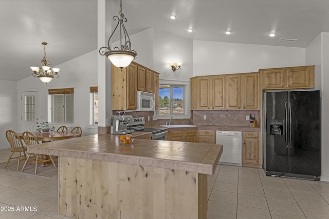 kitchen featuring light tile patterned floors, white appliances, a notable chandelier, and a sink