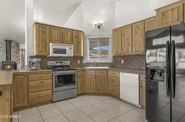 kitchen with a wood stove, white appliances, light tile patterned flooring, and backsplash