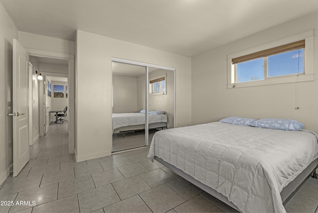 bedroom featuring light tile patterned floors, baseboards, and a closet