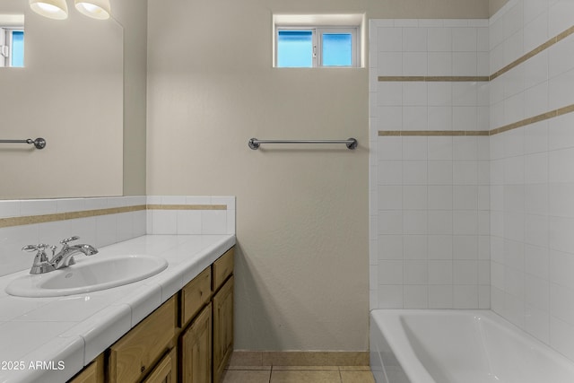 full bath with tub / shower combination, vanity, tile patterned flooring, and baseboards