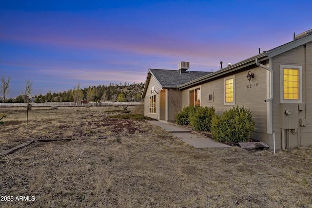 property exterior at dusk featuring fence