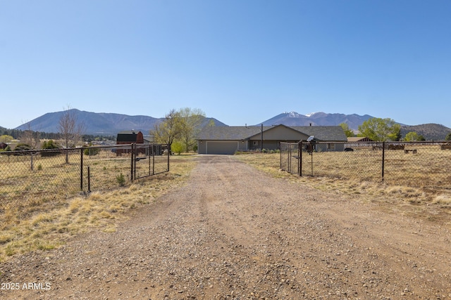 view of street with a gate, a mountain view, driveway, and a gated entry
