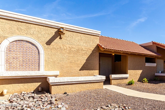 view of property exterior with a tile roof and stucco siding