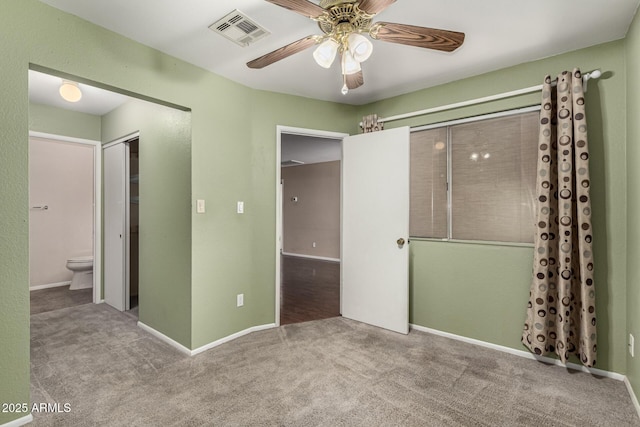 unfurnished bedroom featuring carpet, visible vents, ensuite bathroom, a ceiling fan, and baseboards