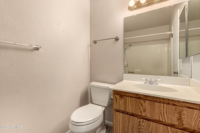 bathroom with toilet, a textured wall, and vanity