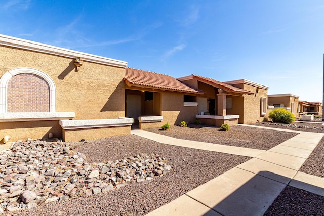 exterior space with a tiled roof and stucco siding