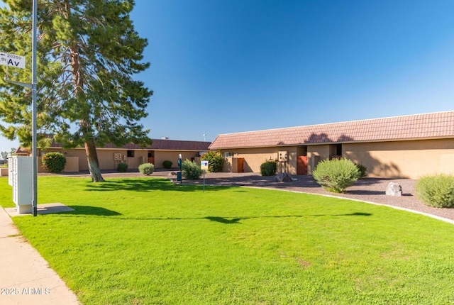 ranch-style home featuring a tiled roof, a front lawn, and stucco siding