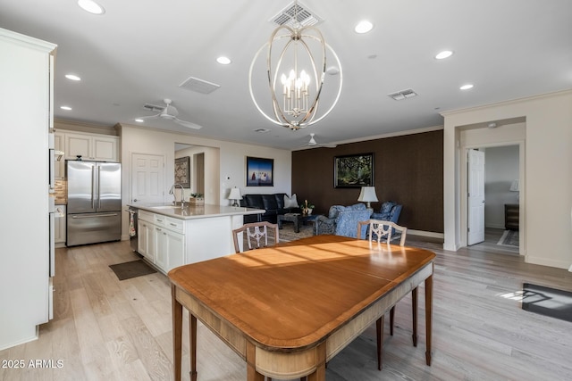 dining space featuring ornamental molding, sink, and light wood-type flooring