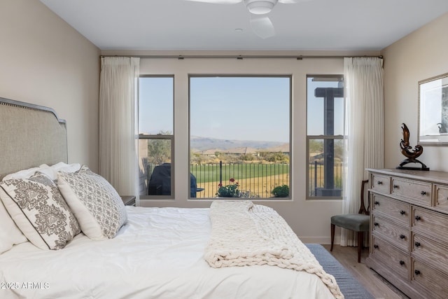 bedroom featuring a mountain view, hardwood / wood-style floors, and ceiling fan