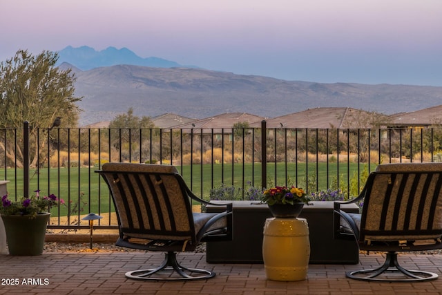 patio terrace at dusk featuring a yard and a mountain view