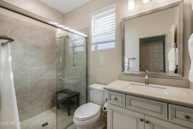 bathroom featuring vanity, a shower with door, and toilet