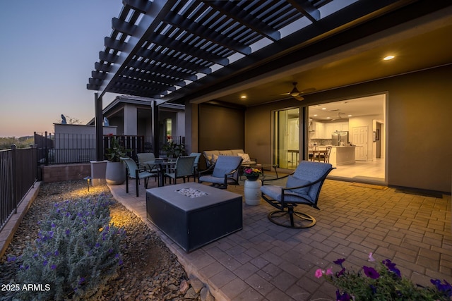 patio terrace at dusk featuring a pergola, an outdoor living space with a fire pit, and ceiling fan