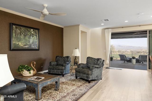 interior space with hardwood / wood-style flooring, ornamental molding, a mountain view, and ceiling fan