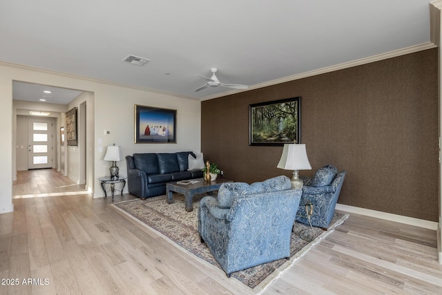 living room featuring light hardwood / wood-style flooring, ornamental molding, and ceiling fan