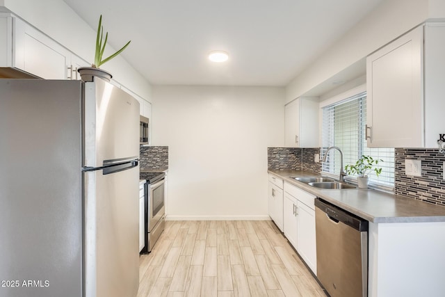 kitchen featuring appliances with stainless steel finishes, tasteful backsplash, light wood-type flooring, white cabinets, and sink