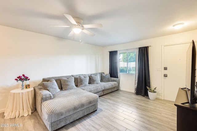 living area featuring light wood finished floors, baseboards, and ceiling fan