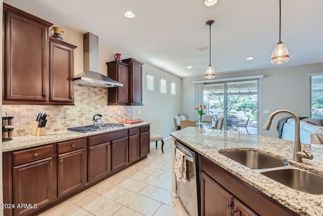 kitchen featuring hanging light fixtures, sink, wall chimney exhaust hood, backsplash, and appliances with stainless steel finishes