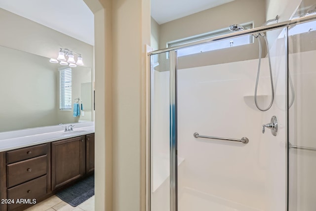 bathroom with walk in shower, vanity, and tile patterned flooring