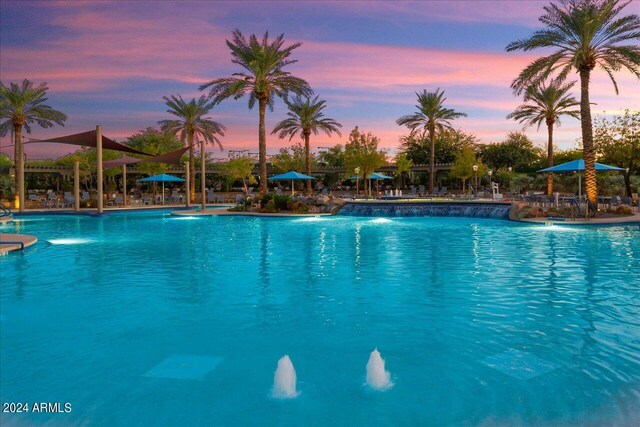 pool at dusk featuring pool water feature