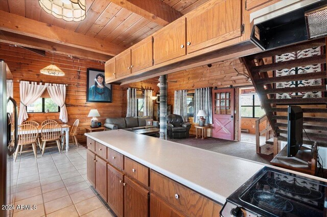 kitchen with a wealth of natural light, beam ceiling, wooden walls, and light tile patterned flooring