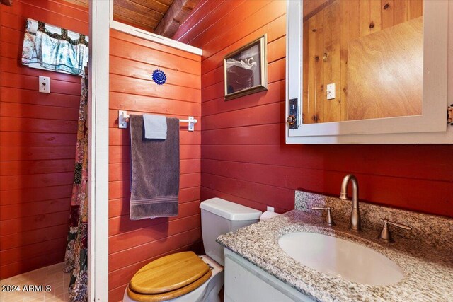 bathroom featuring toilet, wooden walls, wooden ceiling, and vanity