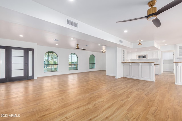 unfurnished living room with ceiling fan and light hardwood / wood-style floors