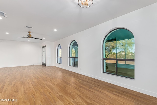 spare room featuring light hardwood / wood-style floors, ceiling fan, and a healthy amount of sunlight