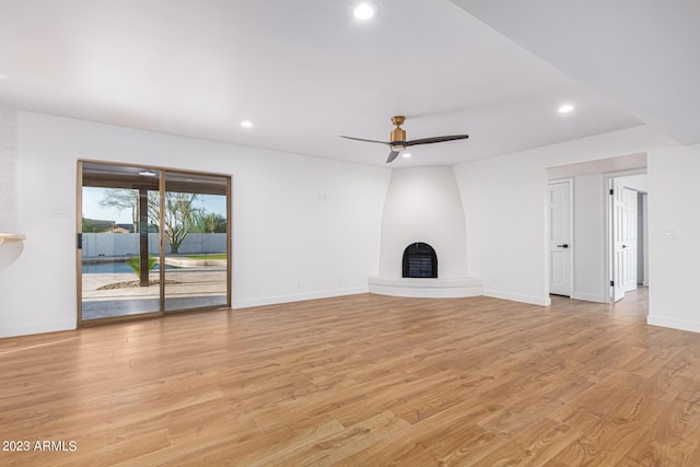 unfurnished living room with ceiling fan, light wood-type flooring, and a fireplace