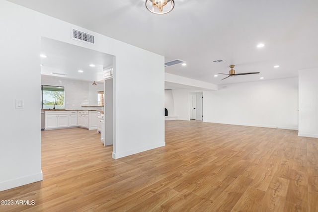 unfurnished living room featuring sink, ceiling fan, and light hardwood / wood-style flooring