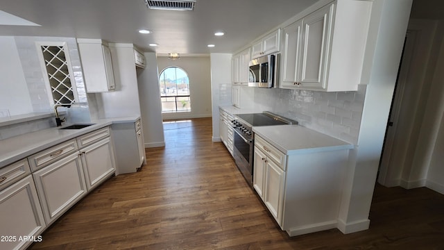 kitchen with tasteful backsplash, dark hardwood / wood-style flooring, white cabinetry, appliances with stainless steel finishes, and sink