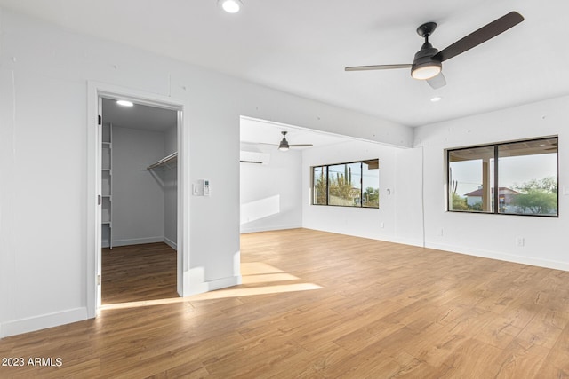 interior space featuring an AC wall unit, a spacious closet, light hardwood / wood-style flooring, a closet, and ceiling fan