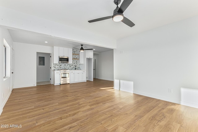 unfurnished living room featuring electric panel, light wood-type flooring, and ceiling fan