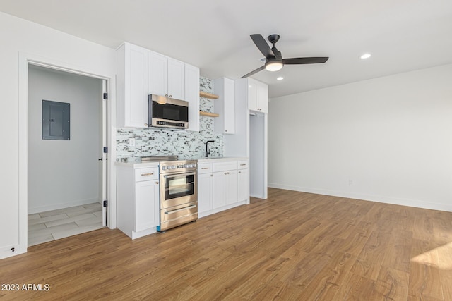 kitchen with appliances with stainless steel finishes, white cabinetry, backsplash, and electric panel