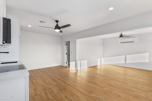 unfurnished living room featuring ceiling fan, light wood-type flooring, a wall mounted air conditioner, and sink