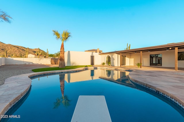 view of pool featuring a diving board, a patio, and a mountain view