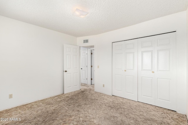 unfurnished bedroom with a closet, a textured ceiling, visible vents, and carpet flooring