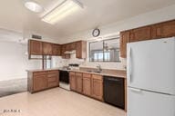 kitchen with light countertops, freestanding refrigerator, a sink, dishwasher, and a peninsula